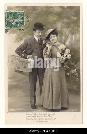Original early 1900's French sentimental tinted greetings postcard - two young lovers, Man wearing a bowler hat, carries the woman's shopping, postally used green stamp on front of postcard France, circa 1911 Stock Photo