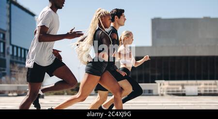 Group of people going running workout together in the city. Diverse group of street runners running in the city. Stock Photo