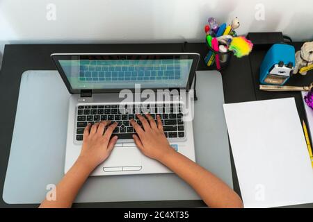 A view from the top of a young student makes use of a laptop for her e-learning class. Stock Photo
