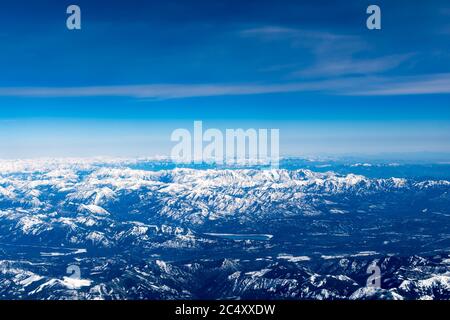 Aerial View of Idaho mountains from the sky while inside an airplane. View of brown mountains and trees covered with snow Stock Photo