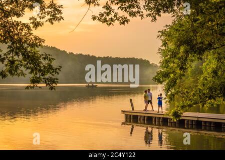 Family photo moment during a fiery sunset along the waterfront at Fort Yargo State Park campground in Winder, Georgia. (USA) Stock Photo