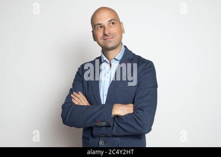 Handsome middle aged bald man is looking up over studio gray wall. Studio shot Stock Photo