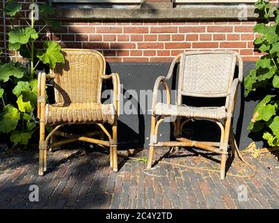 View on two empty old braided rattan chairs, brick wall background Stock Photo