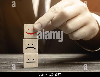 One block with a positive face stands out from the rest of the neutral and negative emotions. Concept of good rating, review and feedback. Satisfied c Stock Photo