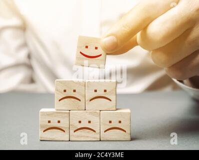 One block with a positive face stands out from the rest of the negative emotions. Concept of good rating, review and feedback. Satisfied customers. Se Stock Photo