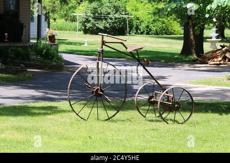 a vintage antique rusty three wheel bicycle bike trike parked on a grass lawn