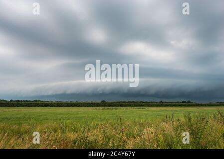 Approaching thunderstorm with arcus (shelf cloud) over plain landscape Stock Photo