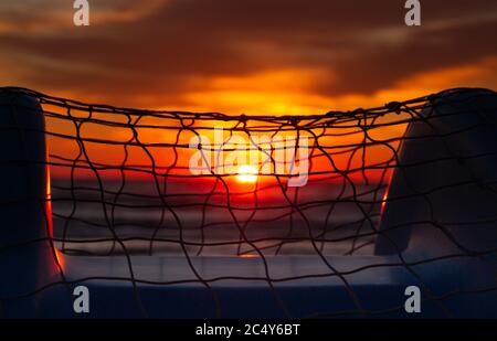 colorful blurred ocean sunrise seen through a fishing net on pedal boat at Rivazzurra (Rimini/Italy) beach Stock Photo