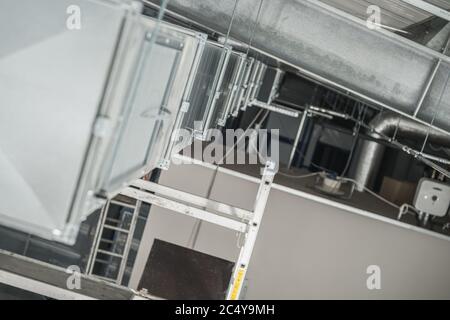 Close Up View Of Silver Metal Air Ventilation Pipe System Hanging From Ceiling Of Large Warehouse. Stock Photo