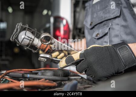 Male Auto Mechanic Picking Correct Tools To Fix Coach Bus In Vehicle Repair Shop. Stock Photo