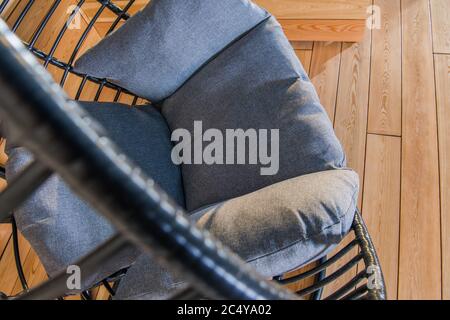 Black Oval Hanging Chair With Gray Comfortable Pillows In Residential Backyard Garden. Stock Photo