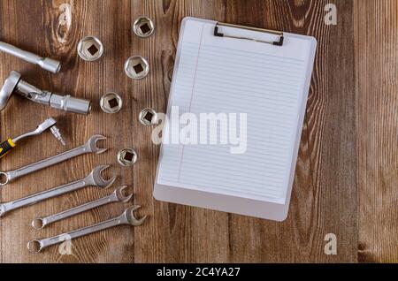 Professional automotive set tool of wrenches chrome tools wit notepad on wood background. Stock Photo