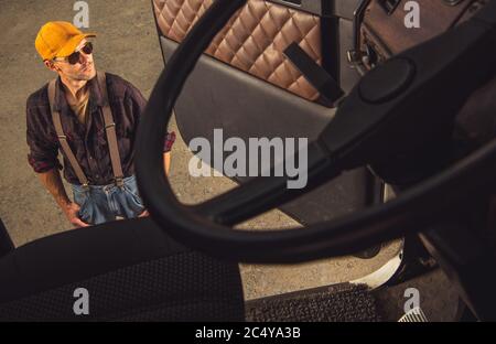 Middle Age Male Trucker Standing Outside Of Vehicle Cab And Looking Around. Stock Photo