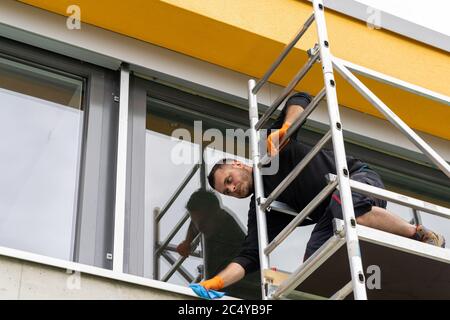 window cleaner on a portable scaffolding rack cwashing windows of a house Stock Photo