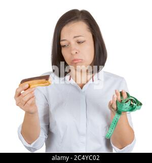 Diet Concept. Beautiful Pretty Young Woman Choosing Between Chocolate Eclair and Health Life with Measuring Tape on a white background Stock Photo