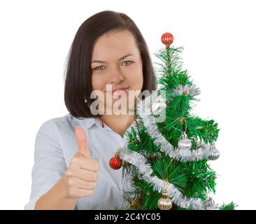 New Year Concept. Beautiful Woman Showing Thumbs Up as OK sign with Decorated Christmas Tree on a white background Stock Photo