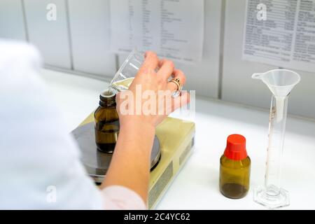 A close up of a female pharmacist mixing chemical liquids on medical scales in a laboratory Stock Photo