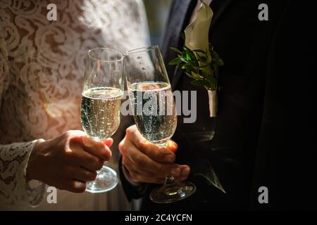 Hands of bride and groom holding champagne glasses with sparkling wine. Wedding celebration concept Stock Photo