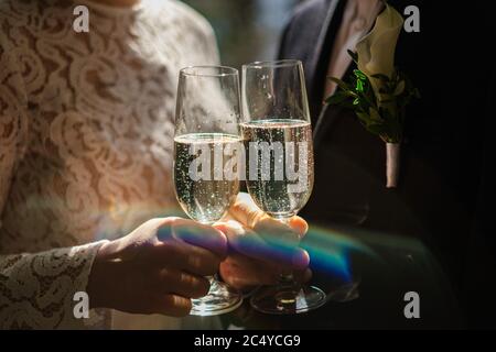 Hands of bride and groom holding champagne glasses with sparkling wine. Wedding celebration concept Stock Photo
