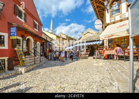 Tourists shop for gifts and souvenirs as diners enjoy a sidewalk cafe on the cobblestone streets of medieval Old Town Mostar, Bosnia. Stock Photo