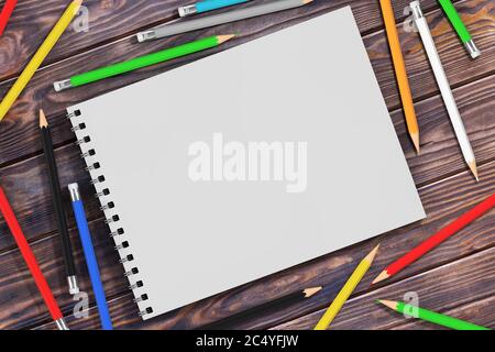 Top View of White Spiral Paper Cover Art Book with Multicolour Pencils on a wooden table. 3d Rendering Stock Photo