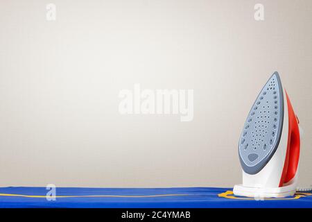 Iron on Ironing Board Against a White Wall with Copy Space extreme closeup Stock Photo