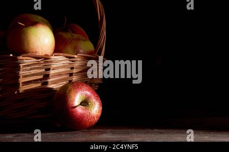 Braided basket with red apples on a black background Stock Photo