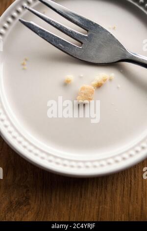 Fork and cake crumbs on an empty white plate Stock Photo