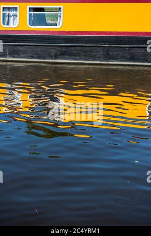 Yellow barge reflected in the waters of a canal in England, UK Stock Photo