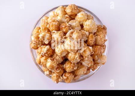 Sweet caramel popcorn in glass bowl. Close up. White background. Top view. Stock Photo