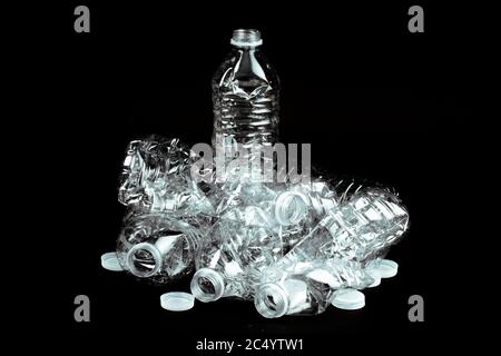 crushed empty clear plastic single use water bottle garbage on a black background Stock Photo
