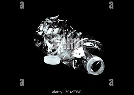 a single crushed empty clear plastic single use water bottle garbage on a black background Stock Photo