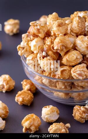Sweet caramel popcorn in glass bowl. Close up. Dark grey background. Stock Photo