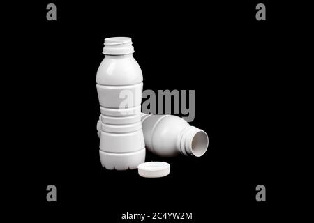 two empty white plastic single use milk bottles on a black background Stock Photo