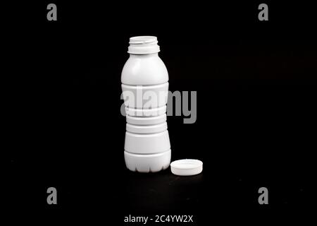 an empty white plastic milk bottle on a black background Stock Photo