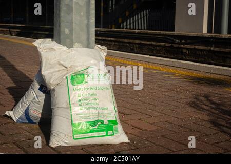 Bags of Ice melt premium de-icer on train station or railway station platform as preparation for bad frosty weather. Stock Photo