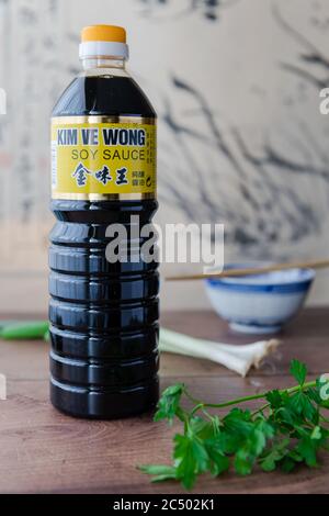 A bottle of Kim Ve Wong brand naturally brewed soy sauce on a kitchen top with parsley and spring onions. Stock Photo