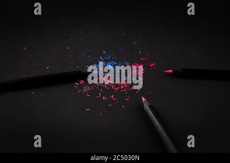 Black, colored pencils, on black background, and shavings from the pencils. Stock Photo