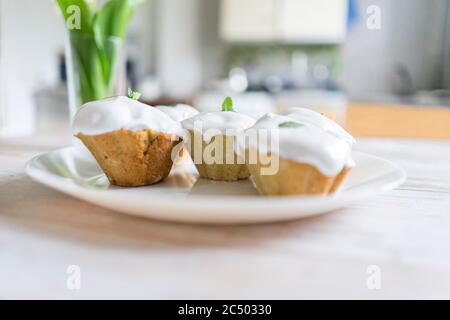 Cupcake with white cream in a plate. Nearby lies a bouquet of lilies of the valley Stock Photo