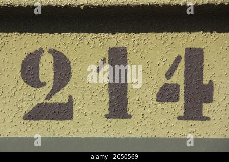 Rough wall painted in two different shades of green and with a number painted on it, 214 Stock Photo