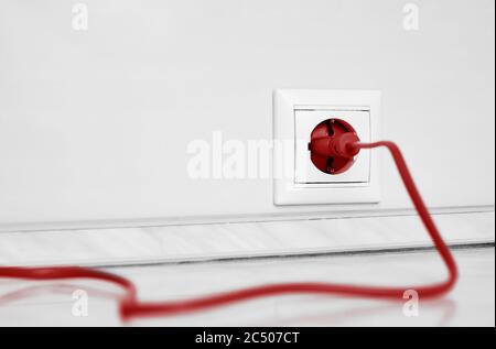 Electric white socket and one plugged in power cord on white wall background Stock Photo
