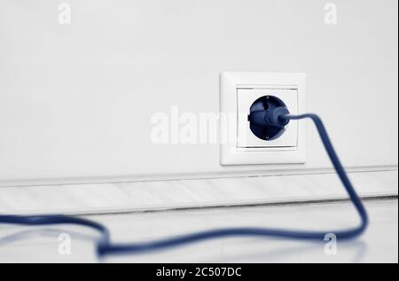 Electric white socket and one plugged in power cord on white wall background Stock Photo