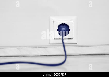 Electric white socket and one plugged in power cord on white wall background Stock Photo