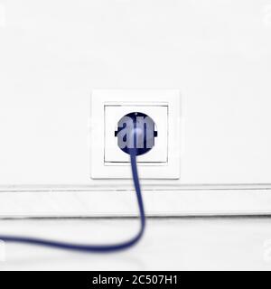 Electric white socket and one plugged in power cord on white wall background Stock Photo