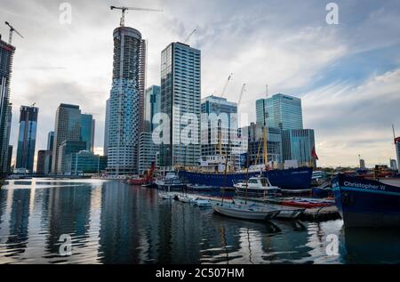 Canary Wharf in late afternoon light with its high rise office buildings casting reflection in the calm water. Stock Photo