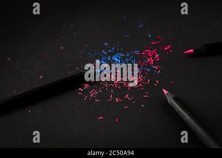 Black, colored pencils, on black background, and shavings from the pencils. Stock Photo