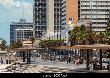 People walking on promenade along modern hotel buildings in Tel Aviv - city on Mediterranean coastline of Israel. Stock Photo