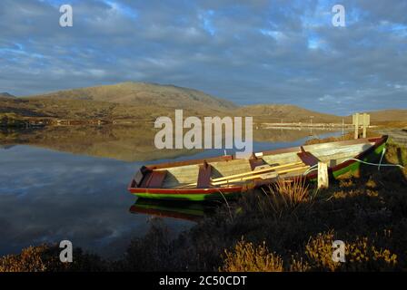 The oars lie idle in a small wooden rowing boat tied up on a still LOCH DRUIDIBEG, SOUTH UIST, OITER HEBRIDES, SCOTLAND Stock Photo