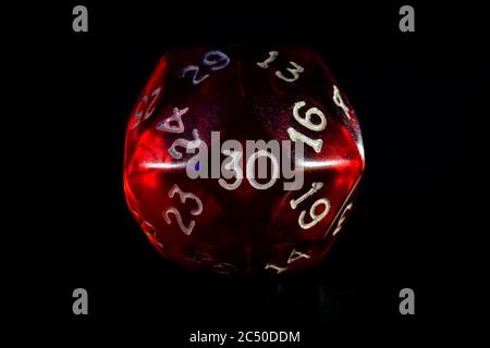 Red role playing game or rpg 30 or thirty sided dice close-up isolated on black. Stock Photo