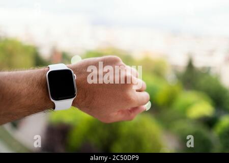 Izmir, Turkey - June 11, 2020: Close up shot of Apple brand 5th generation white colored Apple watch on a mans wrist and defocused green background. Stock Photo